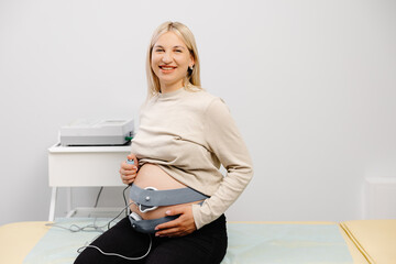 Woman pregnant checking fetal heart beat by fetal monitoring. Expectant mother with midwife...