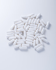 white capsules with vitamins on a white background