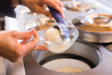 Scoop of creamy ice cream in spoon from the refrigerator container