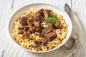 pasta rings topped with braised meat in bowl