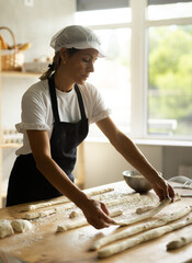 Elderly woman baker rolls out dough