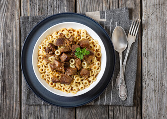 pasta rings topped with braised meat in bowl