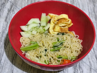 A bowl of Indonesian noodle soup with vegetables and egg.