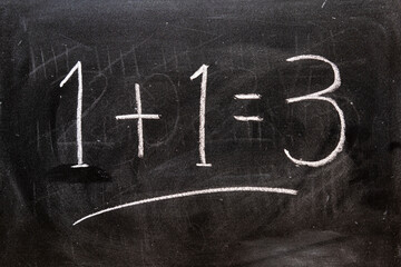 1 + 1 = 3, escrito a mano con tiza en la pizarra