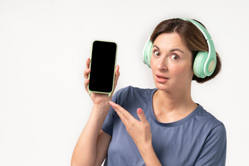 Young beautiful girl in headphones listening to music using her smartphone