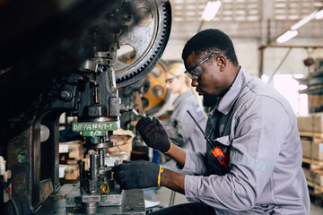 african black male worker working in heavy metal industry factory punching stamping steel machine