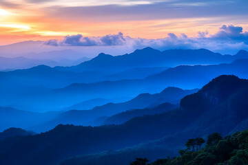 Vibrant sunset illuminates mountain ranges with layers of blue and orange hues near a tranquil valley