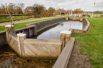 Obraz premium Landscape with wooden lock doors of Buitenweg polder sluice in Utrecht with lush greenery and water.