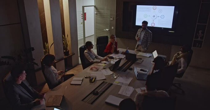 Multiracial people working late in a modern office. A diverse team collaborates on a project during a business meeting. - Powered by Adobe