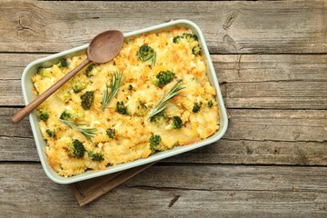 Tasty pasta casserole with cheese, rosemary and broccoli in baking dish on wooden table, top view. Space for text