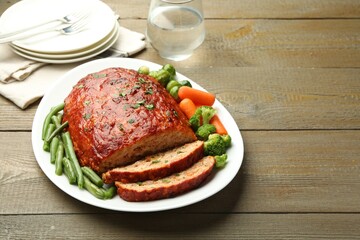 Delicious baked turkey meatloaf with vegetables served on wooden table, space for text