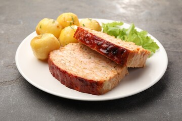 Delicious baked turkey meatloaf, potatoes and lettuce on grey table, closeup
