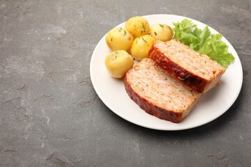 Delicious baked turkey meatloaf, potatoes and lettuce on grey table, space for text
