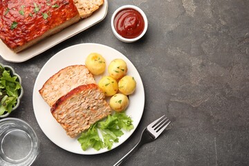 Delicious baked turkey meatloaf with vegetables served on grey table, flat lay. Space for text