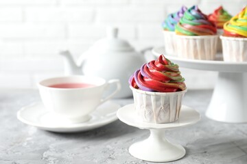 Delicious cupcake with colorful cream on grey textured table, closeup