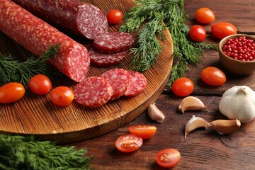 Different smoked sausages, cherry tomatoes and spices on wooden table, closeup