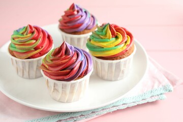 Delicious cupcakes with colorful cream on pink table, closeup
