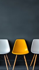 Yellow chair standing out from two white chairs in front of a dark gray wall, concept of diversity and uniqueness
