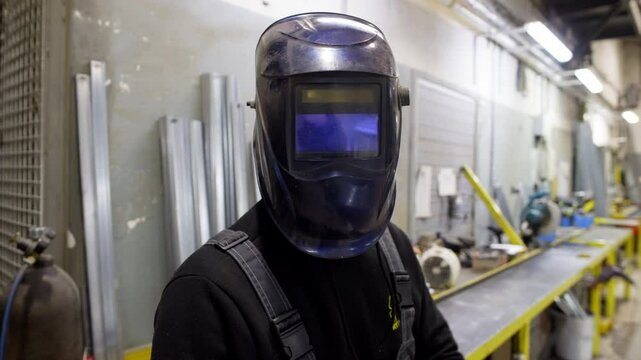 A man wears a special mask for working with welding. He treats difficult work with humor and smiles. High quality 4k footage