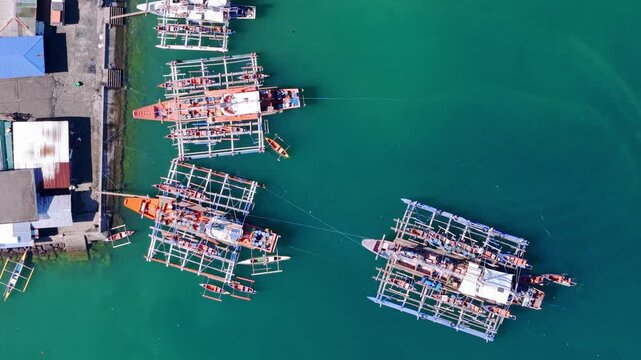 Drone bird's eye view of pump and banca boats moored at Placer, Surigao Del Norte, showcasing local transportation between islands and mainland on a sunny day.
