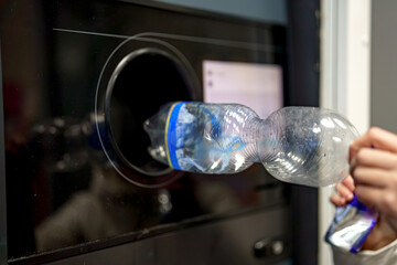 A woman returns plastic bottles to a plastic recycling machine.
