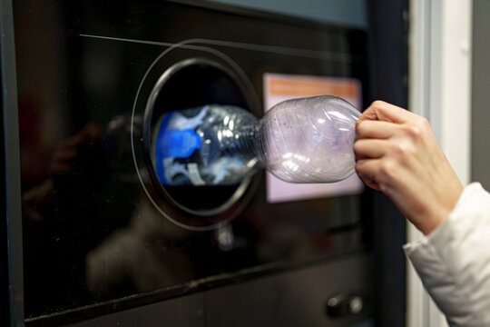 A woman returns plastic bottles to a plastic recycling machine.