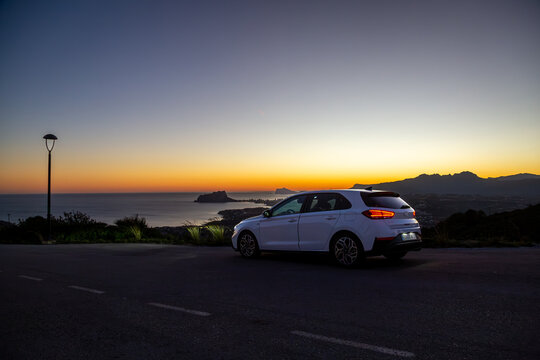 Hyundai i30 along a quiet road by the Spanish coast at sunset, Image shows the white i30 in the final moments of sunlight on a hill overlooking Moraira
