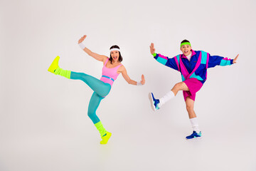 Dynamic duo energetically performing retro aerobics in colorful activewear against a white background, showcasing vibrant 80s style