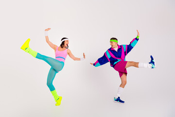 Energetic couple in vibrant retro sportswear performing dynamic dance moves on a white background,...