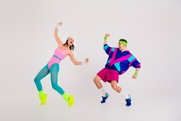 Energetic couple showcasing fun dance moves in vibrant retro outfits on a white background, highlighting fitness and dynamic lifestyle