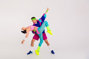 Energetic couple in vibrant retro activewear dancing energetically on a white background, embodying...