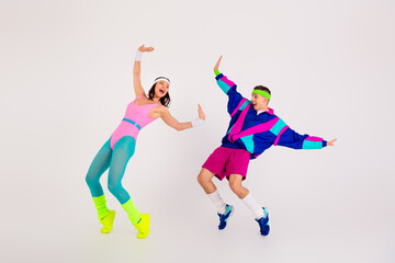 Dynamic couple enjoying a retro aerobic dance workout in colorful 80s activewear on a minimalist...
