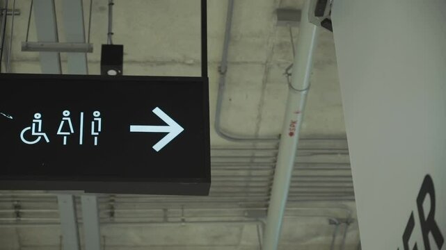 closeup toilet sign with an arrow in a shopping center hanging on the celling  indoors