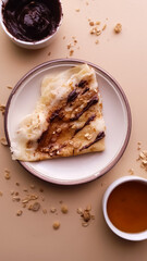 crepe with banana and honey and granola on light brown plate and beige background
