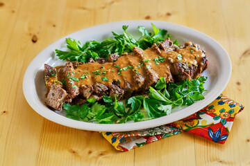 sliced pot roast on a bed of mixed greens