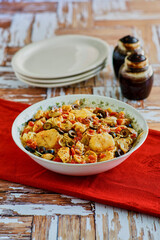 scallop and chicken pasta with garlic, tomatoes and black olives served in a white bowl