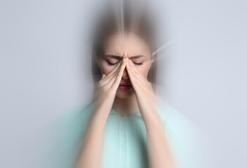 Woman suffering from headache and dizziness on grey background