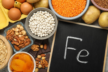 Diet plan for anemia. Different products rich in iron and small chalkboard with Ferrum symbol on table, flat lay. Space for text