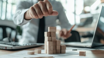 Person constructing a colorful block tower on a wooden desk in a bright indoor environment