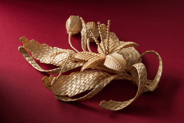 Decoration of straw on a red background. Branch with flowers. Boutonniere made out of straw. Brooch. Straw weaving.