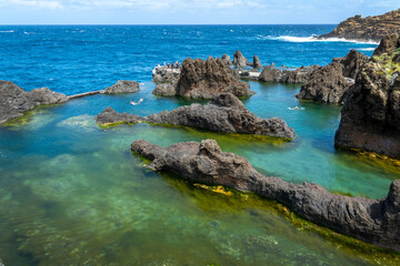 Tourists visiting the natural seawater lava pools in Porto Moniz, Madeira island, Portugal
