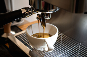 Close-up of espresso pouring from the coffee machine into a coffee cup. Professional coffee brewing