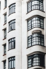 Fototapeta premium A white brick building featuring elegantly curved architecture and rounded windows stands out amidst the hustle and bustle of a vibrant urban area under the bright daylight