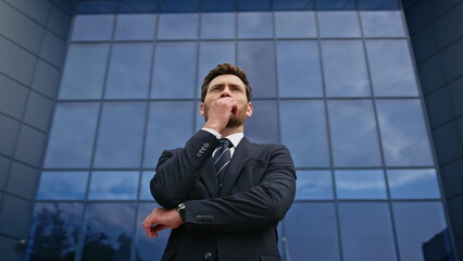 Bearded executive standing street deep in thought near glass office wall closeup