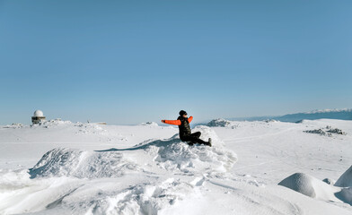 Woman sitting on a stone in the winter snowy mountain 