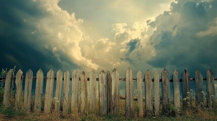 Obraz premium Weathered Wooden Fence with Dramatic Clouds and Soft Light