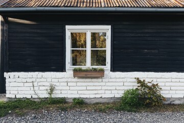 Fototapeta premium This charming rustic house, painted in black and white, features an inviting flower box sitting beneath its window and a gravel path that winds through a lush landscape of greenery.