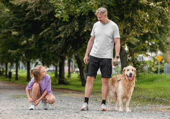 Father Watching As A Girl Ties Shoelaces With A Golden Retriever Dog Nearby