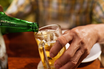 Hand pouring alcohol beverage from green bottle into a glass