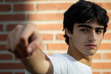 Young man looking directly at the camera with a brick wall as the backdrop, great for portrait or profile shots
